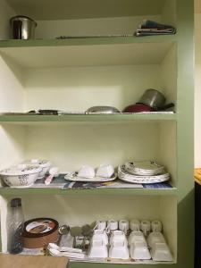 チェンナイにあるKASI'S TNAGAR Home Stayのキッチンにある皿やプレートが置かれた緑色の棚