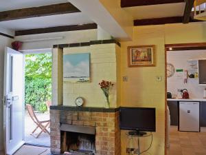 a living room with a brick fireplace with a tv at Crown Cottage in Hartest