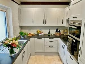 a kitchen with white cabinets and a black counter top at Crown Cottage in Hartest