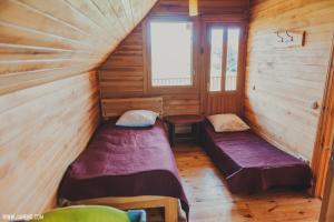 a room with two beds in a wooden cabin at Rudzupuķes in Svente