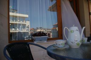 a table with a chair and a table with cups on it at Sea View Apartments in Sozopol