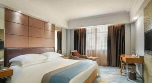 a hotel room with a large bed and a desk at Downtown Hotel in Zhuhai