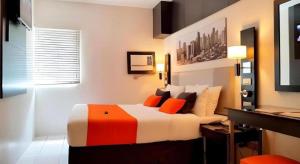 a bedroom with a bed with orange and white pillows at Majestic Hotel Manila - Formerly Octagon Mansion Hotel Manila in Manila