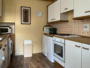 a kitchen with white cabinets and a stove top oven at Shambles Cottage in Ambleside