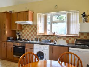 una cucina con un tavolo, un lavello e una lavastoviglie di Black Horse Cottage a Pentraeth