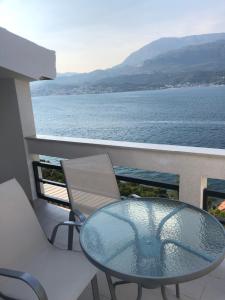 罗瑟Ivanović smeštaj的俯瞰水面的阳台的玻璃桌子和椅子