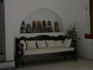 a couch sitting in a room with a wall with paintings at Eri Hotel in Parikia