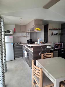 a kitchen with a table and a white refrigerator at 181-Charmettes in Les Mathes
