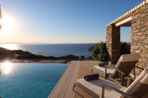 a pool with chairs and the ocean in the background at Aqua Dream Villa in Vourkari