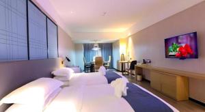 a hotel room with two white beds and a desk at GreenTree Eastern Hotel Hunan Changsha Xinsha Luositang Metro Station in Changsha