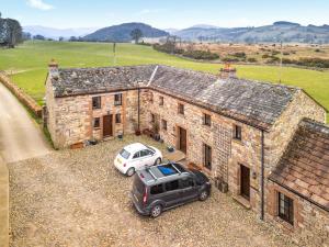 una vecchia casa in pietra con una macchina parcheggiata di fronte di Stable Cottage - B6062 a Pooley Bridge Altre 4 foto