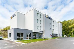 メスにあるACE Hôtel Metzの駐車場付きの白い大きな建物