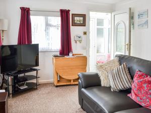 a living room with a couch and a television at Enjoy Your Stay Cottage in Bessingby