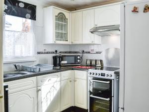 a kitchen with white cabinets and a stove top oven at Enjoy Your Stay Cottage in Bessingby