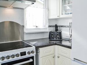 a kitchen with white cabinets and a stove top oven at Enjoy Your Stay Cottage in Bessingby +9 photos