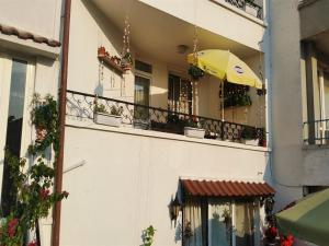 a building with a balcony with a yellow umbrella at Guest House Konomaevi in Sozopol