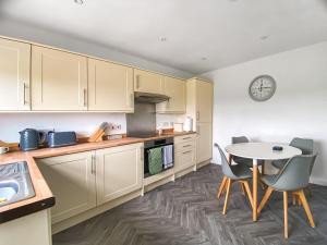 een keuken met witte kasten en een tafel en stoelen bij Guise Cottage Uk46303 in Tough
