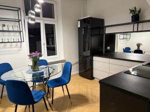 a kitchen and dining room with a glass table and blue chairs at Apartament Zamkowy in Słupsk
