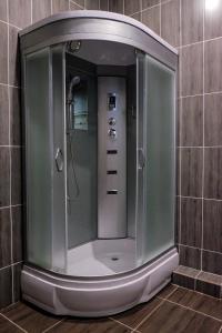 a shower in a tiled bathroom with a mirror at ZhanaOtel Hotel in Aktau