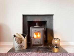 a wood stove with a fire in a fireplace at Academy Street Cottage in Tain