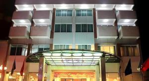 a tall building with a glass entryway and a building at Huu Nghi Hotel in Hai Phong