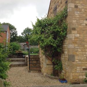 a brick building with a staircase leading to a garden at Hops and the Vines in Shipston on Stour