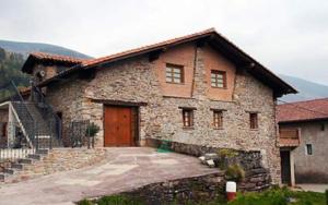 Cette grande maison en pierre est dotée d'une porte en bois et d'escaliers. dans l'établissement Argiñenea, à Berástegui