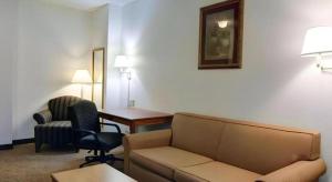 a hotel room with a couch and a desk and chairs at Quality Inn & Suites Airport in Austin