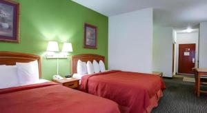 a hotel room with two beds and green walls at Quality Inn & Suites Airport in Austin