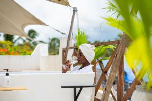 a woman drinking a glass of wine on a patio at Pili Pili Tropical Island in Jambiani