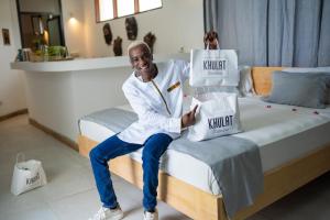 a man sitting on a bed with boxes on it at Pili Pili Tropical Island in Jambiani
