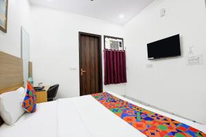 Un dormitorio con una cama y un televisor en la pared. en FabHotel ASP Royal Residency I, en Nueva Delhi