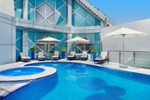 a swimming pool in front of a building with umbrellas at City Seasons Towers Hotel Bur Dubai in Dubai