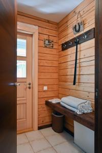a bathroom with a wooden wall with a bench and a door at Romantic cozy house Kirzacinas pirts with sauna close to seaside in Skulte