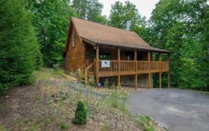 a log cabin with a deck in the woods at Chardonnay Getaway in Pigeon Forge