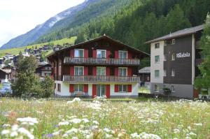 un gran edificio con puertas rojas en un campo de flores en Chalet Moos, en Randa