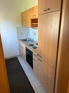 - une cuisine avec des placards en bois, une cuisinière et un évier dans l'établissement Ferienwohnung im Stadtteil Waiern in Feldkirchen in Kärnten, à Feldkirchen in Kärnten