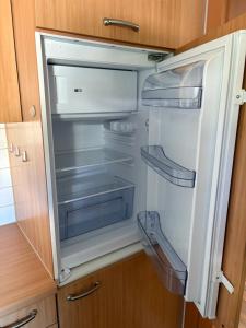 un réfrigérateur vide avec sa porte ouverte dans une cuisine dans l'établissement Ferienwohnung im Stadtteil Waiern in Feldkirchen in Kärnten, à Feldkirchen in Kärnten