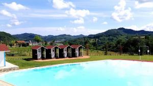 a group of huts with a swimming pool in a resort at Relais Black Horse in Millesimo