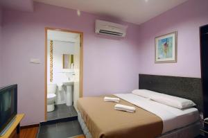 a bedroom with a bed and a tv and a bathroom at Aristo Hotel @ Putatan in Pekan Putatan