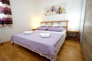 Apartment Vista Makarska في ماكارسكا: غرفة نوم مع سرير كبير مع وسائد أرجوانية