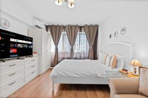 a white bedroom with a bed and a tv at Spitalul Bagdasar & Obregia - Sudului 507 by MRG Apartments in Bucharest