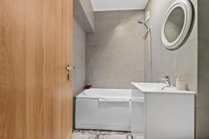 a bathroom with a white tub and a sink at Spitalul Bagdasar & Obregia - Sudului 507 by MRG Apartments in Bucharest +9 photos