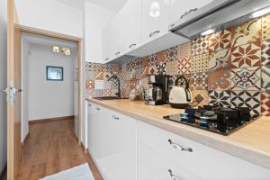 a kitchen with white cabinets and a tile wall at Spitalul Bagdasar & Obregia - Sudului 507 by MRG Apartments in Bucharest