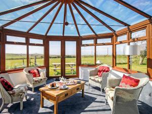 a conservatory with a glass roof with chairs and a table at Beacon Cottage in Llanrian