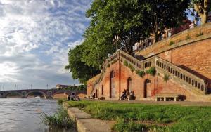 a brick building next to a river with a bridge at T2 Design Hypercentre Capitole in Toulouse