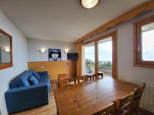 a living room with a table and a blue couch at Vercors 2 020-FAMILLE & MONTAGNE appart 6 pers in Chamrousse