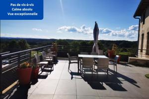 un patio con sedie e un tavolo su un balcone di Maison de Pruns - Piscine - Spacieuse - Calme a Saint-Santin-Cantalès