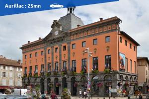 un grande edificio arancione con una torre dell'orologio in cima di Maison de Pruns - Piscine - Spacieuse - Calme a Saint-Santin-Cantalès