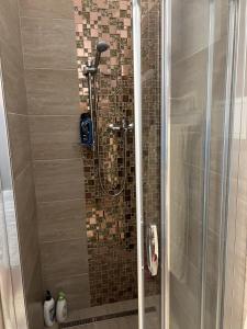 a shower with a glass door with a tile wall at Chata Myslivna v centru Vysočiny Herálec in Žďár nad Sázavou
